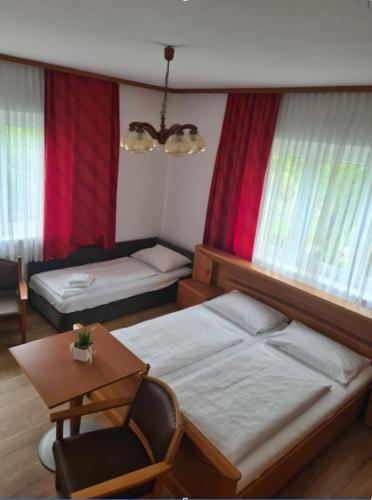 a bedroom with two beds and a chair and a table at HOTEL Jerolitsch in Krumpendorf am Wörthersee