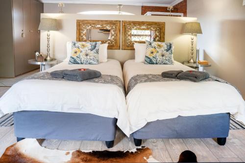 two beds in a bedroom with white and blue at Klip en Kristal Guest House in Bela-Bela