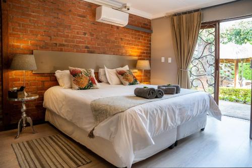 a bedroom with a white bed with a brick wall at Klip en Kristal Guest House in Bela-Bela