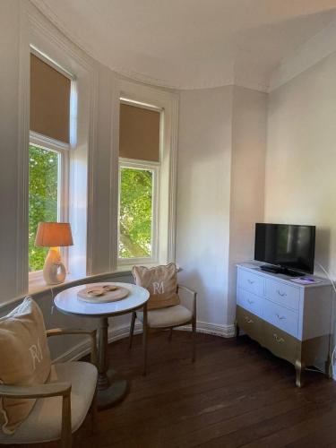 a living room with a tv and a table and chairs at Villa Deichvoigt in Cuxhaven