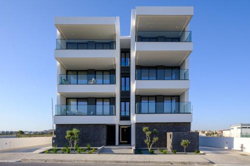a white apartment building with trees in front of it at Artemis 302 - Seaside Stories in Livadhia