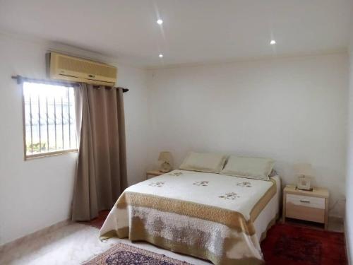 a white bedroom with a bed and a window at Vacation home in an exclusive private development in Higuerote