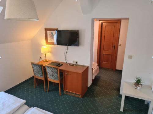 a room with a desk with two chairs and a television at HOTEL Jerolitsch in Krumpendorf am Wörthersee