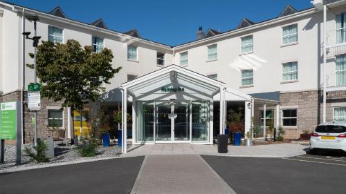 a large white building with a glass entry way at Holiday Inn Bristol Airport by IHG in Redhill