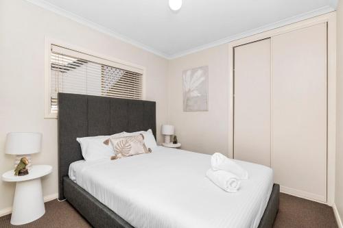 a white bedroom with a large bed and a table at Wagga CBD Apartments in Wagga Wagga
