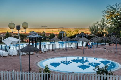 a swimming pool with umbrellas and tables and chairs at Hotel Acosta Vetonia in Almendralejo
