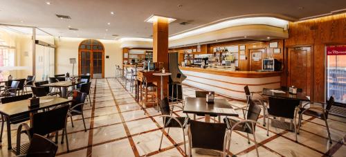 a restaurant with tables and chairs and a bar at Hotel Acosta Vetonia in Almendralejo
