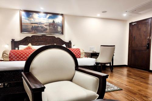 a bedroom with a bed and a chair and a table at Gangotri - A Divine River Retreat in Varanasi