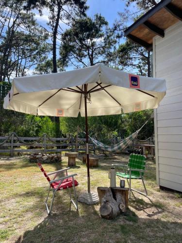 a large white umbrella and two chairs in a yard at Tiny Moor Laguna Garzón in José Ignacio