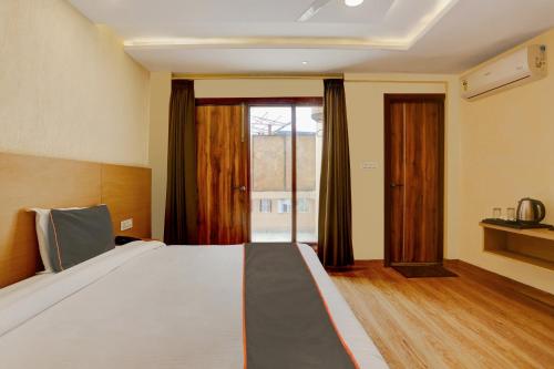 a bedroom with a large bed and a large window at Collection O Dehradun Central Formerly Hotel Orange Residency in Dehradun