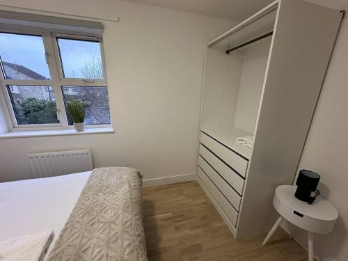 a bedroom with a bed and a dresser and a window at Cosy Home in Churchdown