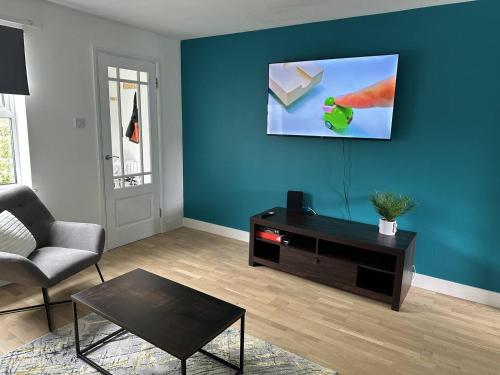 a living room with a couch and a blue wall at Cosy Home in Churchdown