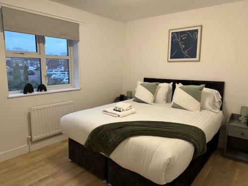 a bedroom with a large bed with white sheets and a window at Cosy Home in Churchdown