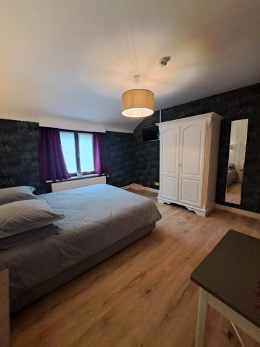 a bedroom with a large bed and a table at Gîte des Roches in Cugnon