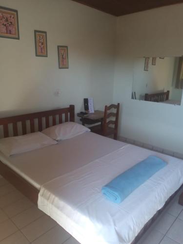 a large white bed with a blue pillow on it at Hotel Park in Valparaíso de Goiás