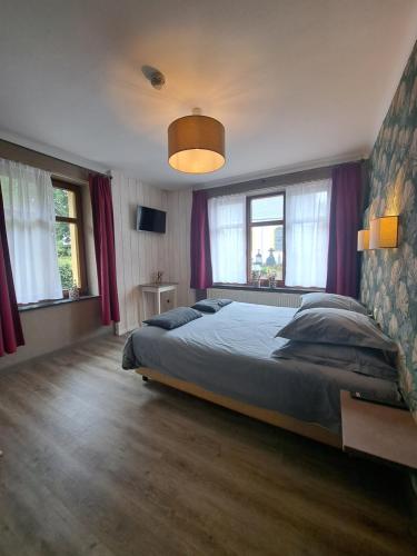 a bedroom with a large bed with purple curtains at Gîte des Roches in Cugnon