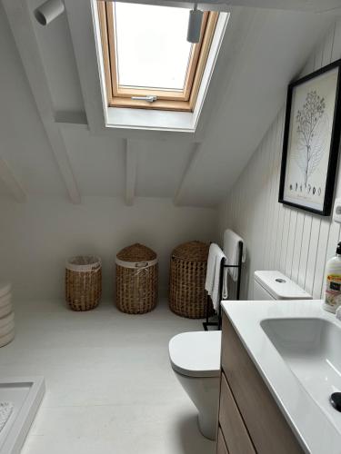 a bathroom with a toilet and a skylight at Royal Barn Loft in Azambuja
