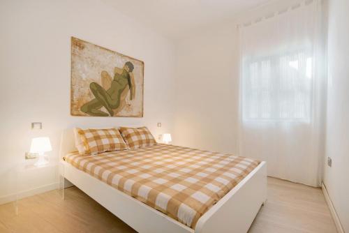 Un dormitorio blanco con una cama con una manta a cuadros. en Balcon de Porteria, en Telde