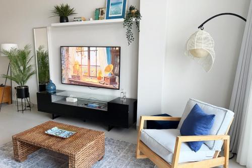 a living room with a tv and a chair at By The Beach - Prime location in Sarūq