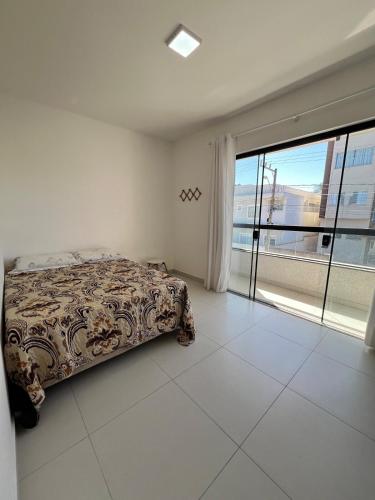 a bedroom with a bed and a large window at Casa em Balneário Picarras in Piçarras