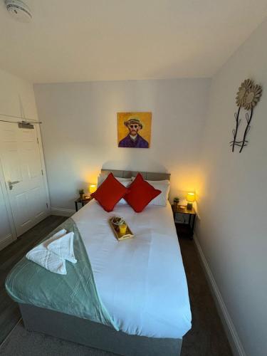 a bedroom with a white bed with red pillows at Central Peterborough Studio 6 in Peterborough