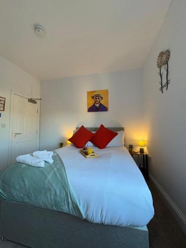 une chambre avec un grand lit blanc avec des oreillers rouges dans l'établissement Peterborough Modern Studio 6, à Peterborough