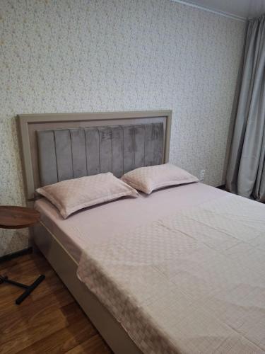 a bedroom with a bed with two pillows on it at Уютная 2-х комнатная квартира in Rudny