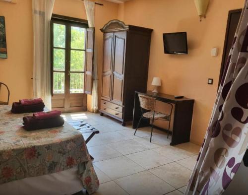 a bedroom with a bed and a desk and a television at Charming rustic house - near river and forest in La Cellera de Ter