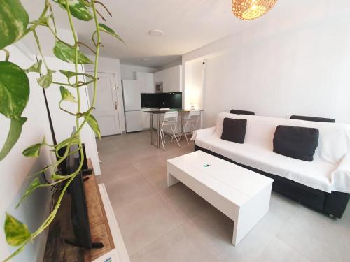 Una sala de estar con un sofá blanco y una mesa. en Alquilaencanarias Medano Lago Azul, en El Médano