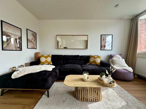 a living room with a black couch and a table at Ferienhaus Meerzeit-Hooksiel in Hooksiel