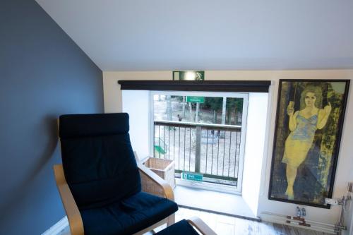 a living room with a blue chair and a window at Norrängens Alpacka - Det lilla boutiquehotellet med en fluffy twist ! in Sala