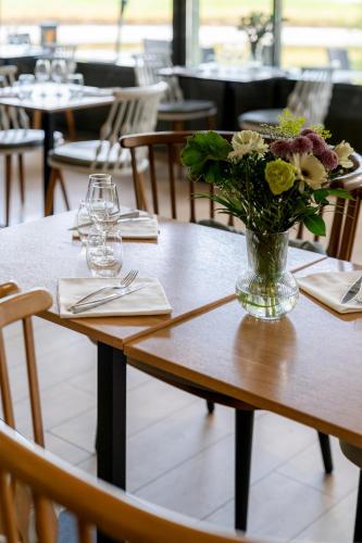 a vase of flowers on a table in a restaurant at Mercure Orléans Portes de Sologne in Ardon