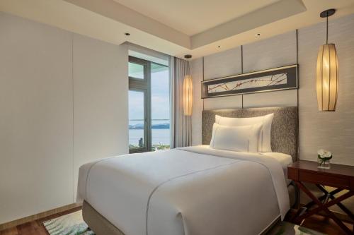 a bedroom with a large white bed and a window at Shenzhen Dameisha Kingkey Palace Hotel in Shenzhen