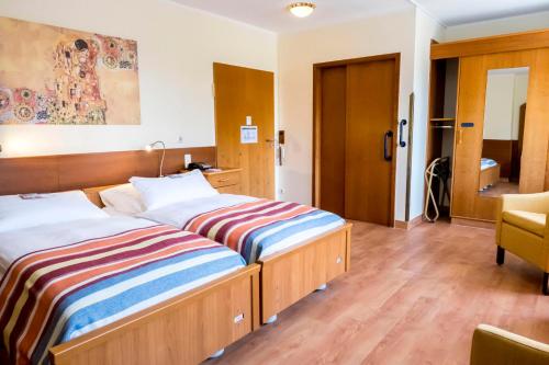 a hotel room with two beds and a chair at Heidehotel Bad Bevensen in Bad Bevensen