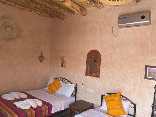 a room with two beds in a room with a fan at Riad Dades Birds in Boumalne