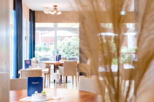 a dining room with tables and chairs and a window at Heidehotel Bad Bevensen in Bad Bevensen