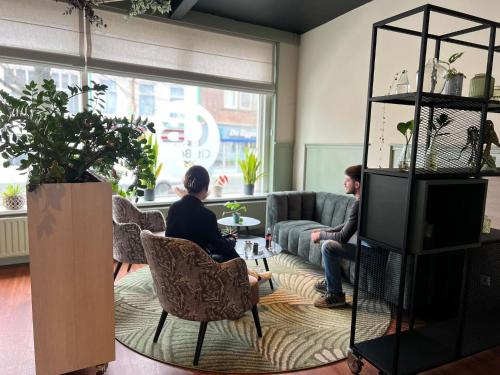 two people sitting in a living room with a tv at City2Beach Hotel in Vlissingen