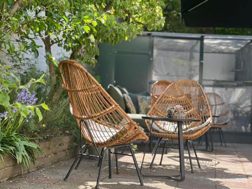 three wicker chairs and a table in a garden at City2Beach Hotel in Vlissingen