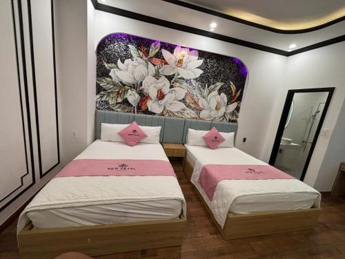 two beds in a room with a painting on the wall at New Pearl Hotel HCM in Ho Chi Minh City