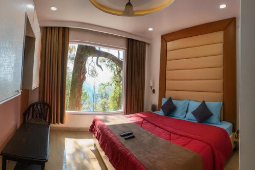 a bedroom with a large bed with a window at Jasmine Mountain View Retreat - Mall Road Dalhousie in Dalhousie