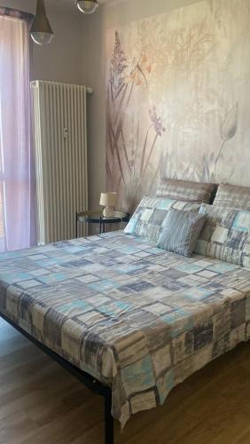 a bedroom with a large bed with a painting on the wall at Room&Go Alba - Home Langhe in Alba