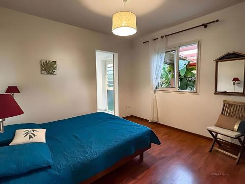 a bedroom with a blue bed and a chair and a window at Ty Lodge in Les Trois Mares