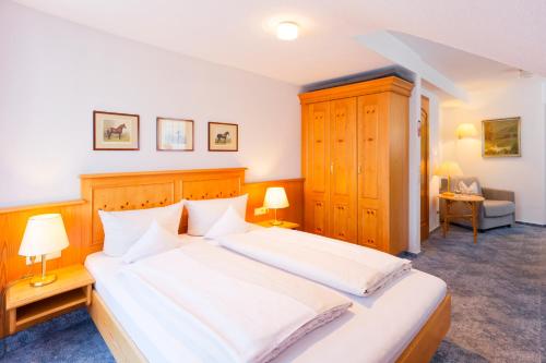 a bedroom with a large bed with white sheets at Hotel Gasthaus Adler in Glottertal
