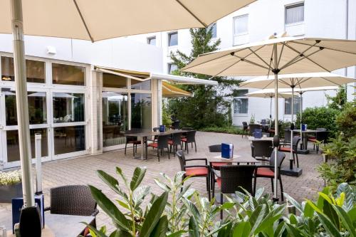 an outdoor patio with tables and chairs and umbrellas at Heidehotel Bad Bevensen in Bad Bevensen