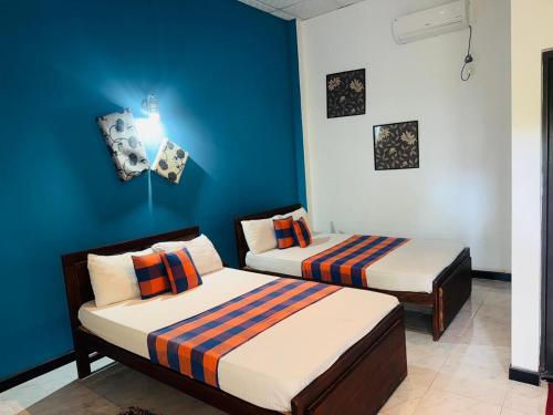 Dos camas en una habitación con paredes azules. en Hotel Winrose Tissamaharama, en Tissamaharama