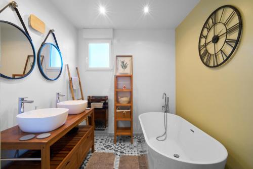a bathroom with two sinks and a large clock on the wall at Maison de vacances Avec Piscine in Loubejac
