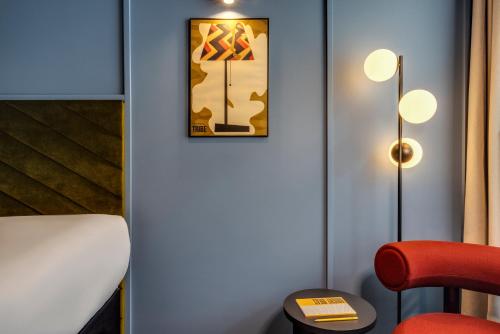 a room with a red chair and a picture on the wall at TRIBE Krakow Old Town in Kraków