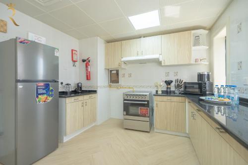 a kitchen with a stainless steel refrigerator and wooden cabinets at Coastal Luxury 4BR Apartment with Private Balcony in Abu Dhabi