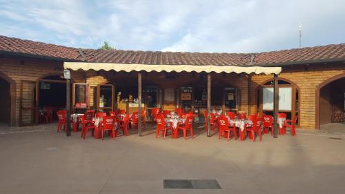 a group of red tables and chairs in front of a building at Camping Paradiso - Aranciona 7 in Viareggio