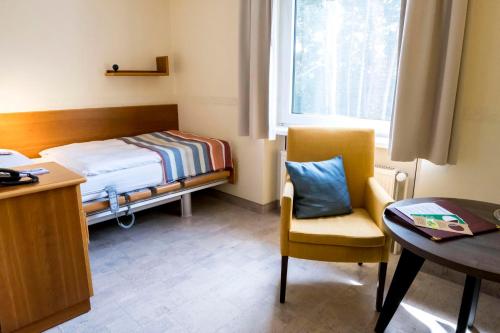 a small room with a bed and a table and a chair at Heidehotel Bad Bevensen in Bad Bevensen